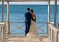 A couple standing at the end of a white pier gazebo overlooking the Caribbean at Grand Palladium Jamaica