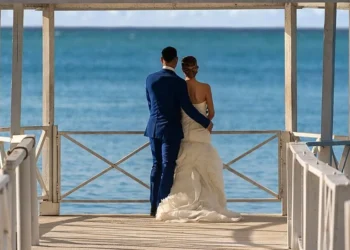 A couple standing at the end of a white pier gazebo overlooking the Caribbean at Grand Palladium Jamaica
