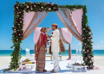 Couple under a floral mandap on the beach at Grand Palladium Costa Mujeres
