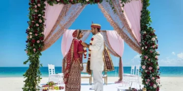 Couple under a floral mandap on the beach at Grand Palladium Costa Mujeres