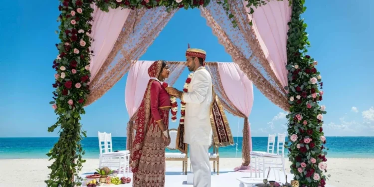 Couple under a floral mandap on the beach at Grand Palladium Costa Mujeres