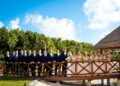 A bride and groom in a navy suit embrace on a wooden bridge framed by palms at The Grand at Moon Palace Cancun