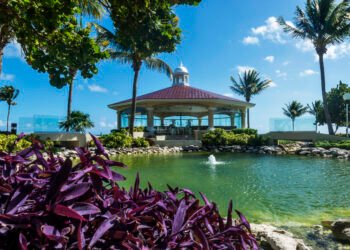 The Chapel of the Immaculate Conception at Moon Palace Cancun, a domed white chapel with a cupola and red tiled roof set beside a landscaped water feature and palm trees