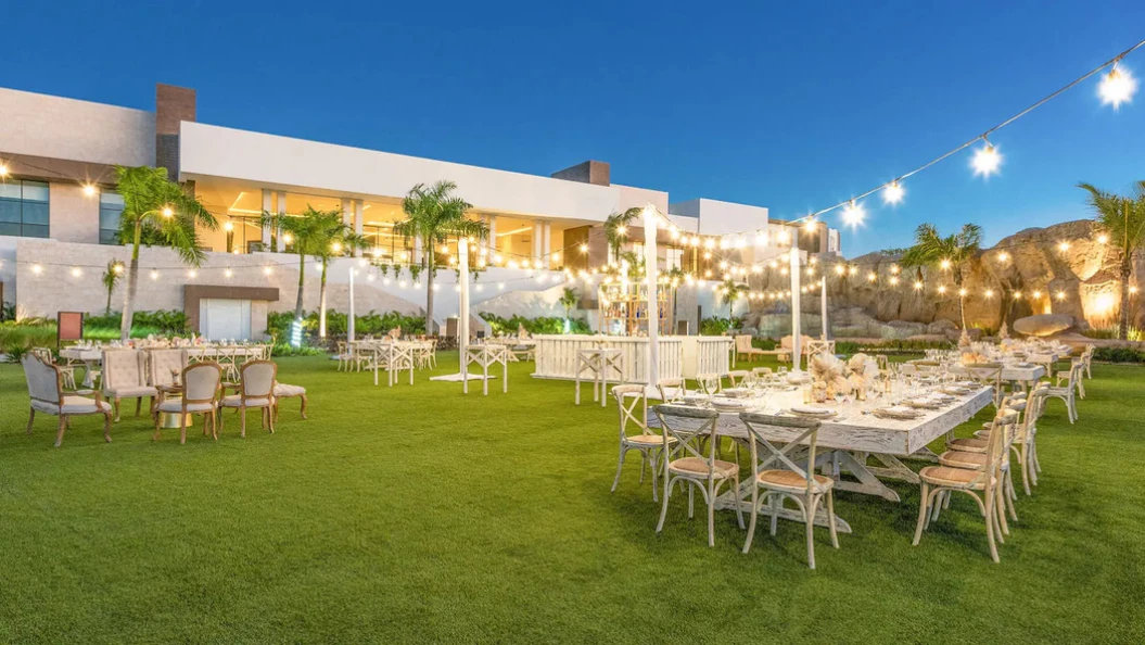 Evening reception set on the Larimar Lawn at Hyatt Ziva Cap Cana with long tables and festoon lighting