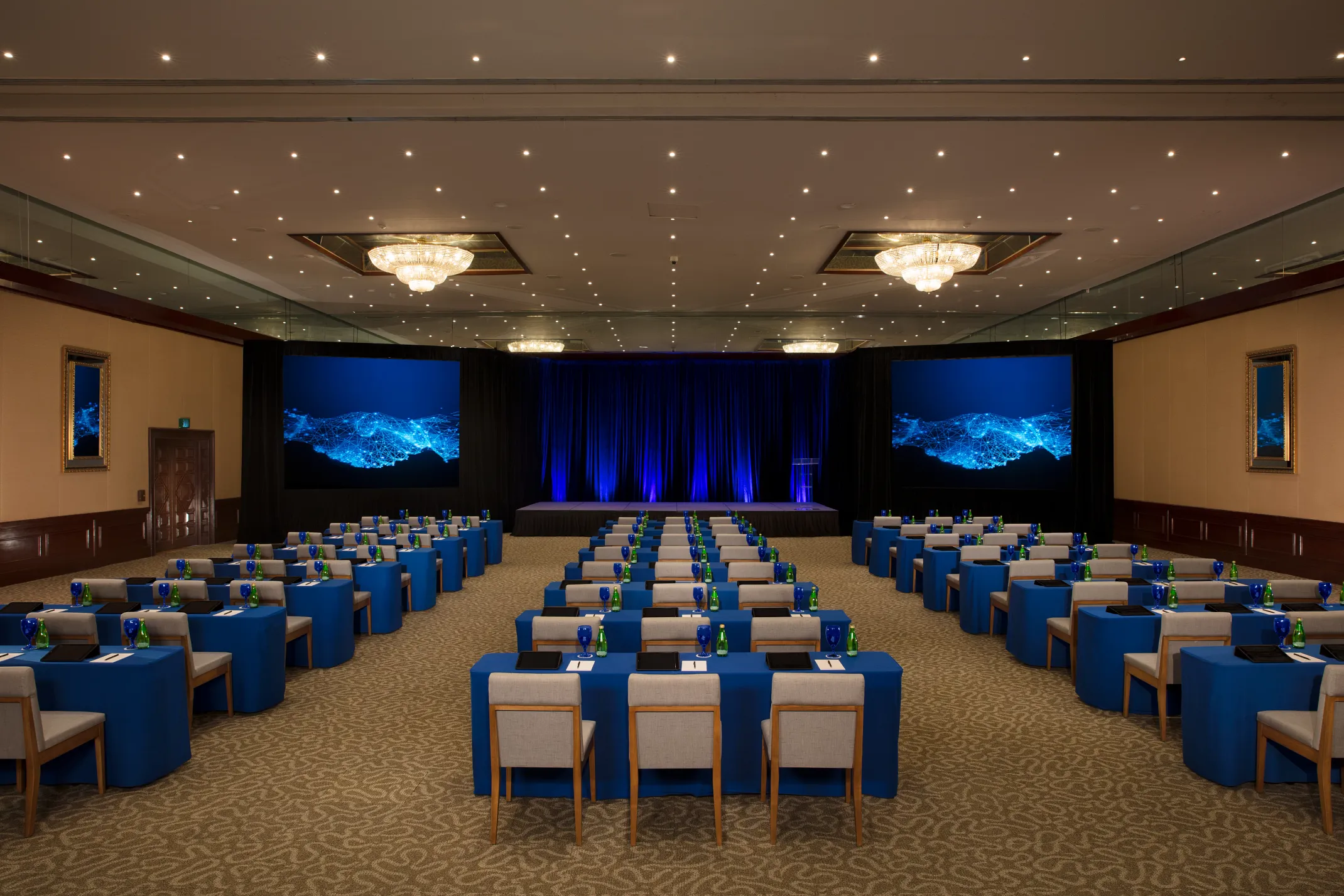 A large indoor ballroom at Dreams Sapphire Resort & Spa set with round tables and a stage, showing the scale of the resort's 300-capacity indoor event space